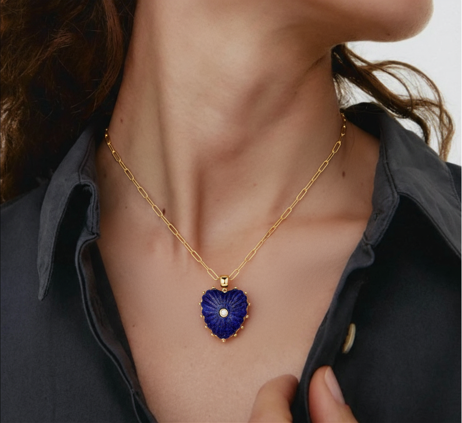 Gold necklace with a blue heart-shaped pendant worn by a person.